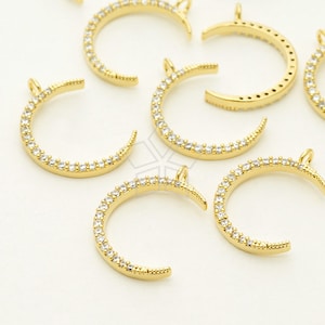 May include: A group of gold crescent moon charms with clear crystal accents. The charms have a loop at the top for attaching to jewelry.