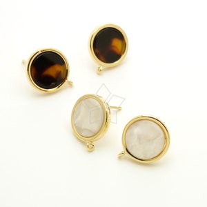 May include: Four gold-toned earring findings with round, flat, decorative tops. Two tops are brown and black tortoise shell pattern and two are white with a pearlescent finish.