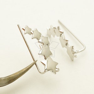 Puede incluir: Pendientes de plata en forma de estrella con un diseño curvo. Los pendientes están hechos de una sola pieza de metal y tienen un cierre de gancho.
