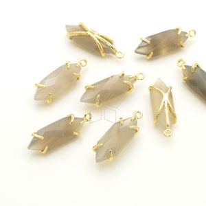 May include: Several faceted, elongated gray gemstone pendants with gold-colored metal accents. Each pendant has a loop at the top for stringing. The gold metal frames the gray stone, with some having a cage-like design.