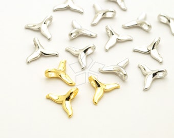 May include: A collection of silver and gold whale tail charms. The charms are in the shape of a whale tail and have a loop at the top for attaching to jewelry.