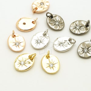 Könnte beinhalten: Sortiment an ovalen Metall-Anhängern mit einem Sternburst-Design und einem klaren Strassstein in der Mitte. Die Anhänger sind in Gold-, Silber- und Gunmetal-Finish erhältlich.