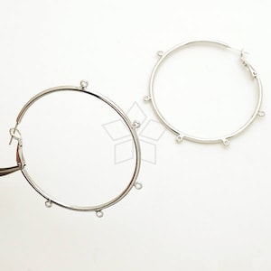 May include: Two silver hoop earrings with five jump rings on each hoop. The hoops are about 2 inches in diameter.