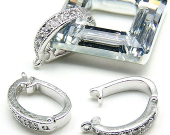 May include: Two silver-toned, oval-shaped clasps with a row of clear crystals. The clasps are open and ready to be attached to a necklace or bracelet.