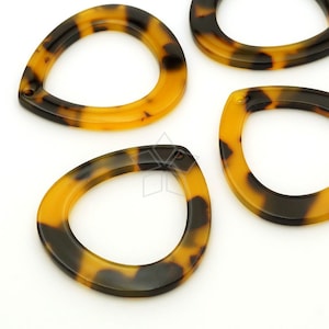 May include: Four brown and black tortoise shell plastic teardrop shaped rings with a hole in the top.