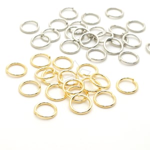 May include: A pile of gold and silver jump rings. The jump rings are small and round, and they are perfect for jewelry making.