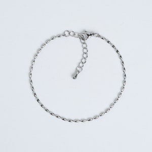 May include: A silver chain bracelet with an oval link design and a lobster clasp closure.