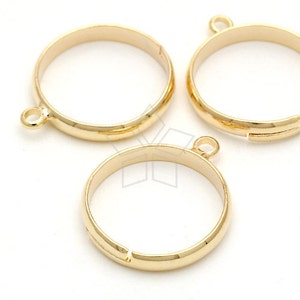 May include: Three gold-toned metal ring blanks with a small loop on the top. The rings are open on one side and can be used for jewelry making.