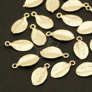 May include: A collection of gold-toned metal leaf charms with a textured surface. The charms have a loop at the top for attaching to jewelry or other crafts.