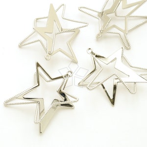 Pode incluir: Cinco pingentes de metal prateado em forma de estrela com uma borda de contas. As estrelas estão sobrepostas.