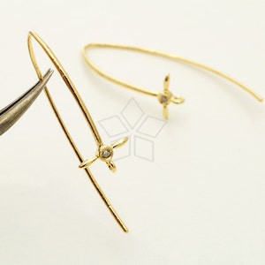 May include: A pair of gold-toned earrings with a small clear stone in the centre of each earring. The earrings are shaped like a flower with four petals.