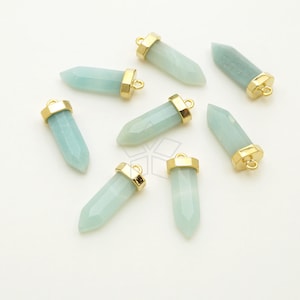 May include: Eight gold-plated pendants with light blue gemstone tips. The pendants are shaped like a pointed crystal and have a loop at the top for attaching to jewelry.