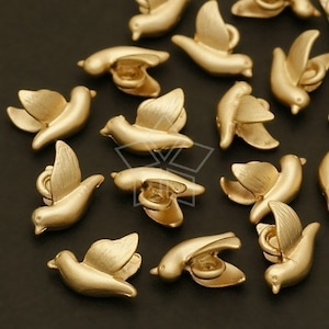 May include: A collection of gold-toned metal bird charms. The charms are in the shape of a stylised bird with a small loop at the top for attaching to jewellery or other crafts.