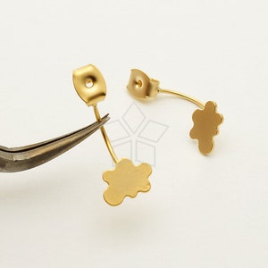 May include: Two gold-tone earring backs with a flower-shaped design. The earring backs are made of metal and have a post that can be inserted into an earring.