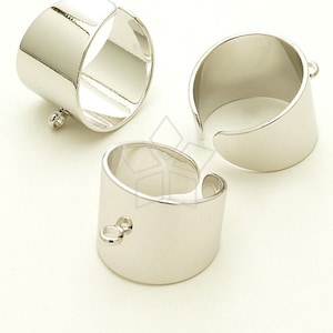 Puede incluir: Tres anillos plateados abiertos con un acabado pulido. Dos anillos tienen pequeños bucles adjuntos. Los anillos son cilíndricos con una abertura curva, exhibidos sobre un fondo blanco.