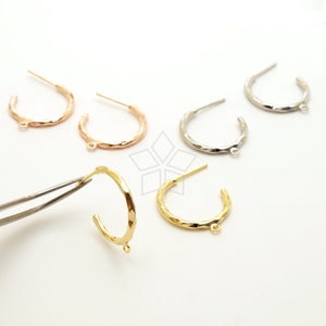May include: Three pairs of hoop earrings in gold, silver, and rose gold. The hoops are textured and have a small loop at the bottom.