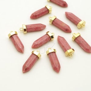 May include: A collection of ten pink gemstone pendants with gold-toned metal caps and jump rings. The pendants are in the shape of a long, pointed teardrop.