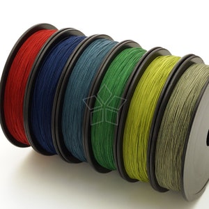 May include: Six spools of thread in different colors: red, navy blue, dark teal, forest green, olive green, and khaki. The spools are wound with thread and are arranged in a row.
