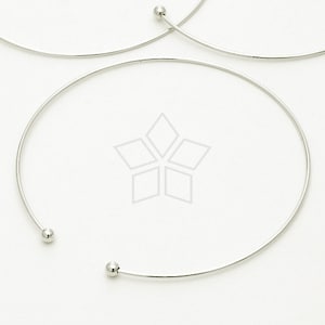 Può includere: Un girocollo in argento con due piccole sfere rotonde alle estremità.