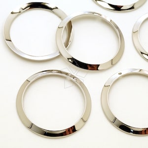 May include: Six silver-toned metal rings with a beveled edge. The rings are approximately 1 inch in diameter.