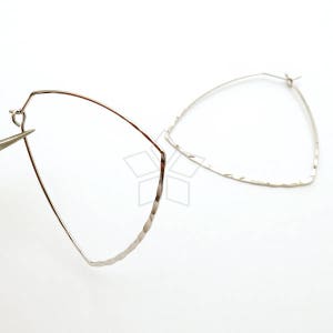 May include: A pair of silver hammered hoop earrings. The earrings are in the shape of a triangle with rounded edges.