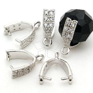 May include: Silver-coloured jewellery findings with a U-shaped design, encrusted with small, clear gemstones. The findings have a loop for attaching to other jewellery components. One finding is attached to a black, faceted bead. Ideal for jewellery making.