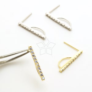 Pode incluir: Três pares de brincos com um design de barra. Dois pares são de prata com strass transparentes e um par é de ouro com strass transparentes.