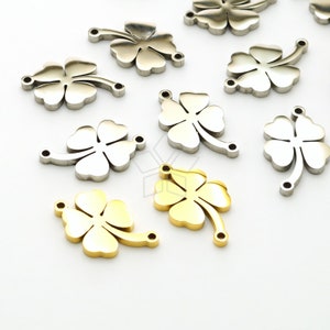 Puede incluir: Una colección de dijes de trébol de cuatro hojas en plata y oro con dos agujeros para sujetar a joyas u otras artesanías.