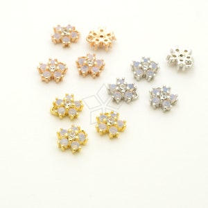 May include: Assortment of flower-shaped charms with clear stones, available in gold, rose gold, and silver finishes. The charms have a loop for attaching to jewelry.