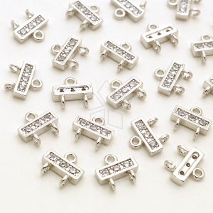 May include: A collection of silver-toned metal connector charms with clear crystal accents. Each charm has two loops on either end and a row of crystals in the center.