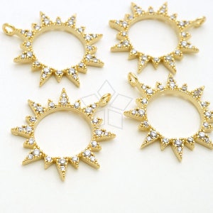 Puede incluir: Cuatro dijes de sol de tono dorado con acentos de cristal transparente. Cada dije presenta un diseño circular con un sol puntiagudo alrededor del borde.