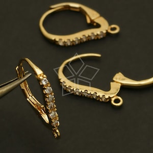 Puede incluir: Dos ganchos para pendientes de tono dorado con detalles de cristal transparente. Los ganchos están diseñados para ser utilizados con una variedad de pendientes.