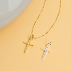 Puede incluir: Un collar de cadena dorada con un colgante de cruz dorada y un colgante de cruz plateada.