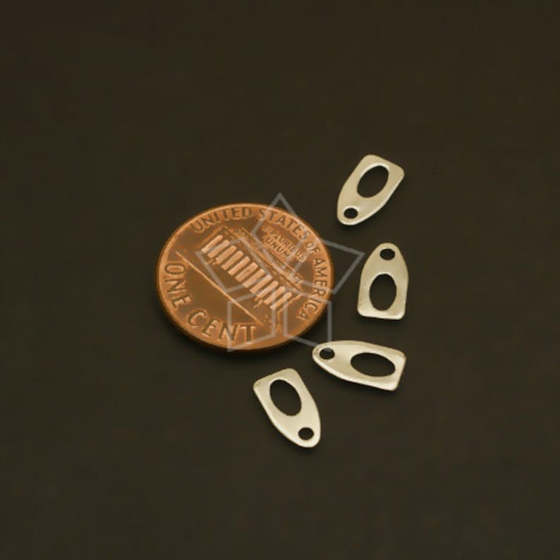 May include: Five silver metal charms in the shape of a teardrop with a small hole at the top. The charms are about the size of a US penny.