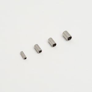 May include: Four silver metal tubes of varying sizes. The tubes are hollow and have a smooth, shiny finish.