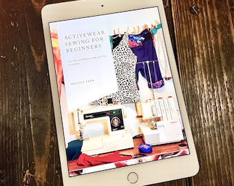 May include: A tablet screen displaying a book cover for "Activewear Sewing for Beginners" by Melissa Fehr. The cover features a leopard print top, a pair of shorts, and a sewing machine.