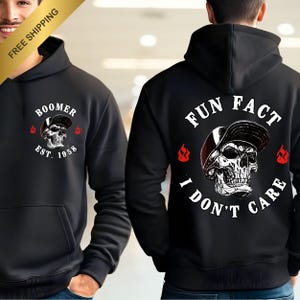 May include: Black hoodie featuring a skull graphic wearing a baseball cap. The front reads "Boomer Est. 1958", the back says "Fun Fact I Don't Care". The design incorporates flames.
