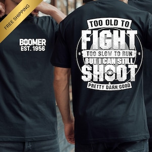 May include: Black t-shirts with white text. One shirt reads "BOOMER EST. 1956" on the front. The other shirt has "TOO OLD TO FIGHT, TOO SLOW TO RUN, BUT I CAN STILL SHOOT, PRETTY DARN GOOD" on the back.