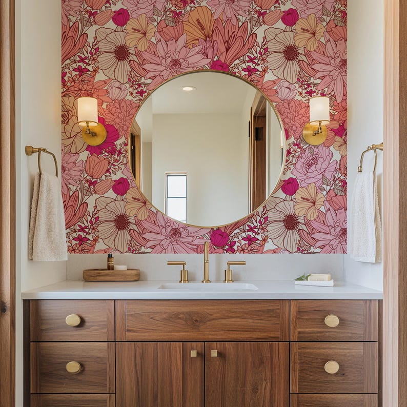 May include: A bathroom vanity with a white countertop and wooden cabinets. The vanity has a round mirror with a gold frame and a floral wallpaper behind it. There are two gold sconces on either side of the mirror.