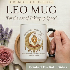 May include: White ceramic Leo mug with a black handle and rim. The mug features a lion illustration on a crescent moon, with text that reads "The Leo Wellness Society" and "Regal, Confident & Dramatically Mild". The mug is printed on both sides.