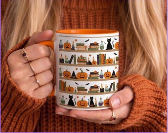 May include: A white ceramic mug with an orange interior and handle, featuring a repeating pattern of horizontal shelves decorated with orange pumpkins, stacks of colorful books, black cats, lit candles, and small glass potion bottles.