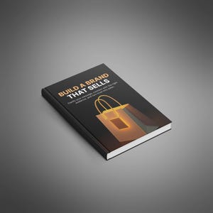 May include: A hardcover book titled "BUILD A BRAND THAT SELLS" with a black cover and gold lettering. The cover features a stylized shopping bag graphic. The book's subtitle reads, "Clarify your message, connect with the right audience, and turn trust into sales."