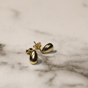 May include: A pair of gold teardrop shaped stud earrings.