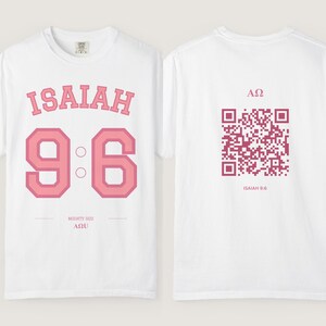 May include: A white t-shirt featuring pink text and graphics. The front displays the word ISAIAH, the number 9:6, and the text MIGHTY GOD AΩ. The back features a pink QR code with the symbols AΩ and the text ISAIAH 9:6 below it.