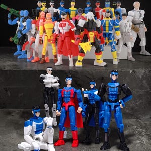 May include: A collection of colorful action figures in various poses. The figures are dressed in superhero-like costumes with a variety of colors, including blue, red, yellow, and white. Some figures are holding weapons.