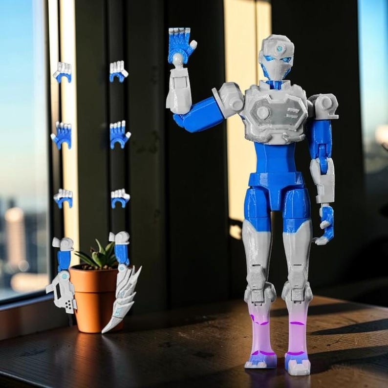 Pode incluir: Uma figura de rob&ocirc; articulada azul, branca e cinza com m&atilde;os intercambi&aacute;veis. O rob&ocirc; tem um design detalhado, com um torso e membros azuis, e detalhes brancos e cinza. M&atilde;os adicionais s&atilde;o exibidas &agrave; esquerda do rob&ocirc;, junto com uma pequena planta em vaso.