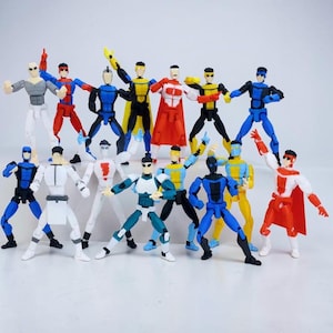 Könnte beinhalten: Eine Sammlung von beweglichen Actionfiguren in verschiedenen Superhelden-Kostümen. Die Figuren sind hauptsächlich in Blau-, Rot-, Gelb- und Weißtönen gehalten, mit schwarzen Akzenten. Jede Figur hat ein einzigartiges Design mit Umhängen, Masken und anderem Zubehör.
