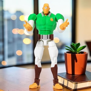Könnte beinhalten: Eine grün-weiße Actionfigur mit einem einzelnen Auge, die ein grünes Hemd und eine weiße Hose trägt. Die Figur hat braune Stiefel und einen braunen Gürtel. Die Figur steht auf einer Holzoberfläche.