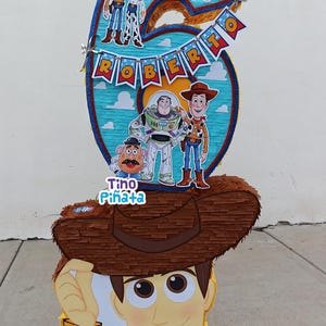 May include: A white ceramic mug with a black handle and the text "But First, Coffee" in a bold, black font. The mug is set against a blurred background, suggesting a cozy setting.