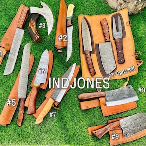 May include: A collection of handcrafted knives and a small axe with wooden handles and leather sheaths, arranged on a green surface. The set includes various blade shapes and sizes, with the text "IND JONES" visible.